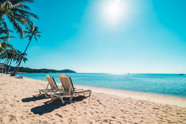 Imagem de uma praia em dia ensolarado, com mar azul, areia branquinha e duas cadeiras