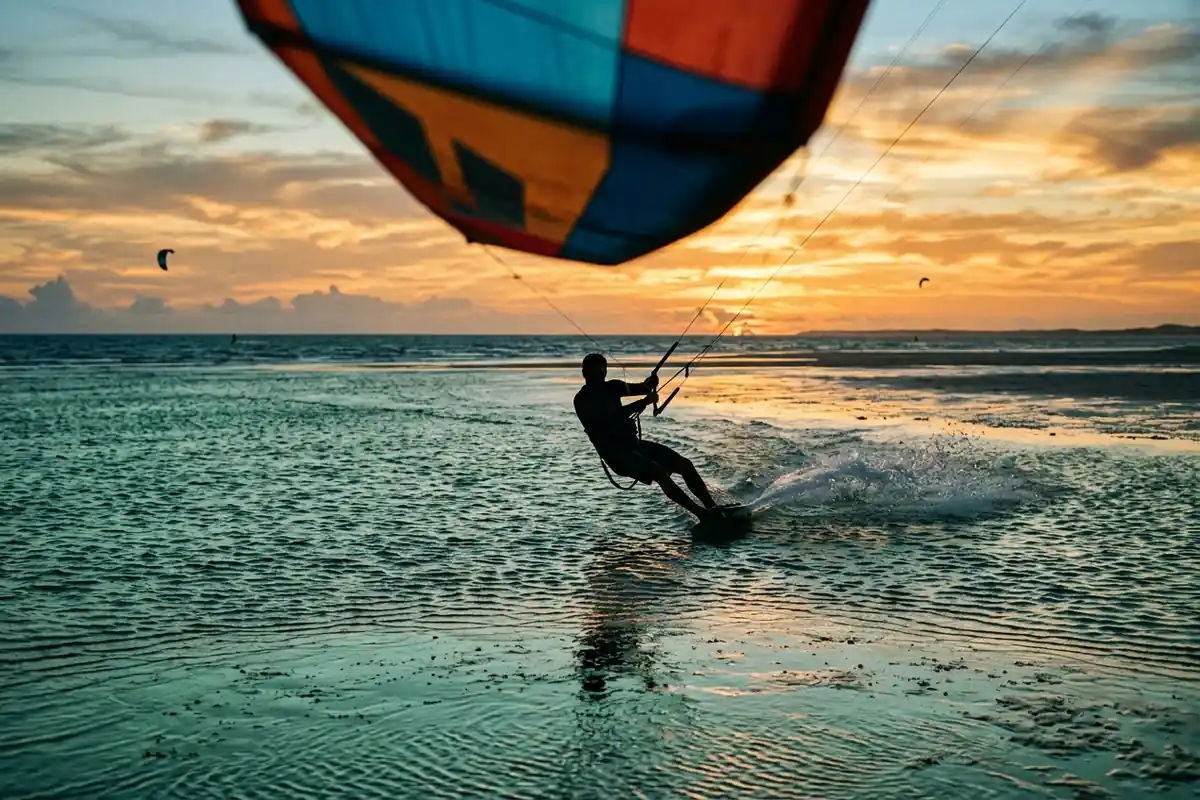 Kitesurfista cruzando a água rasa de Barra Grande com a vela inflada ao vento
