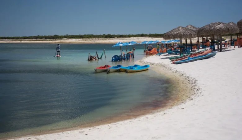 Vista paradisíaca da vila de Jericoacoara com mar azul e dunas ao fundo