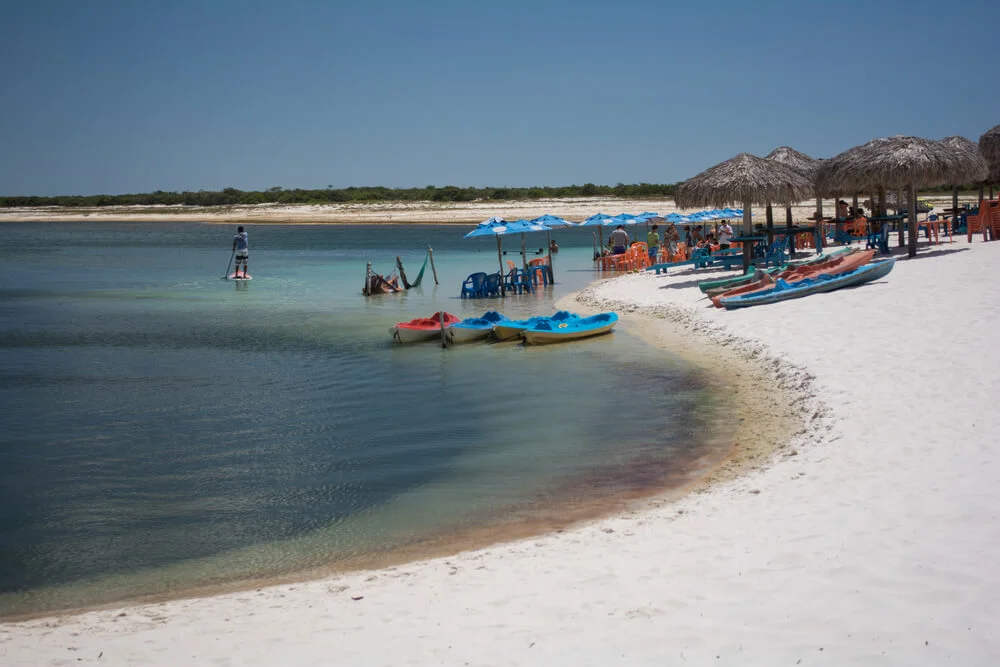 Vista paradisíaca da vila de Jericoacoara com mar azul e dunas ao fundo