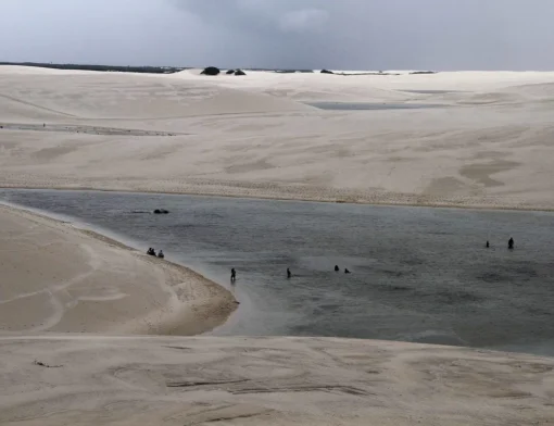 Banhistas na Lagoa Betânia, entre dunas brancas de Santo Amaro do Maranhão, nos Lençóis Maranhenses, sob céu nublado