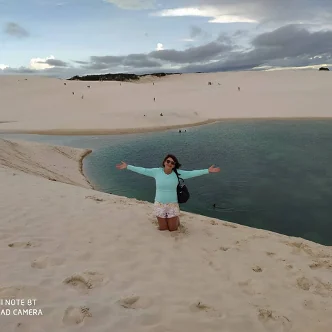 Visitante em duna com lagoa de águas esverdeadas nos Lençóis Maranhenses, próximo a Santo Amaro