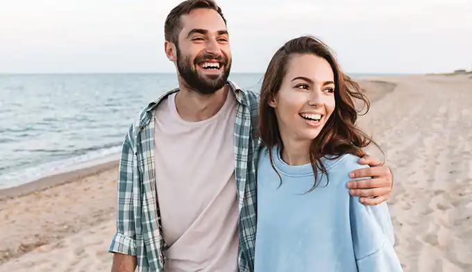 Casal em viagem de lua de mel contemplando o pôr do sol na Rota das Emoções