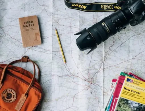 Mesa de planejamento de viagem com mapa, câmera fotográfica e roteiro de destinos turísticos